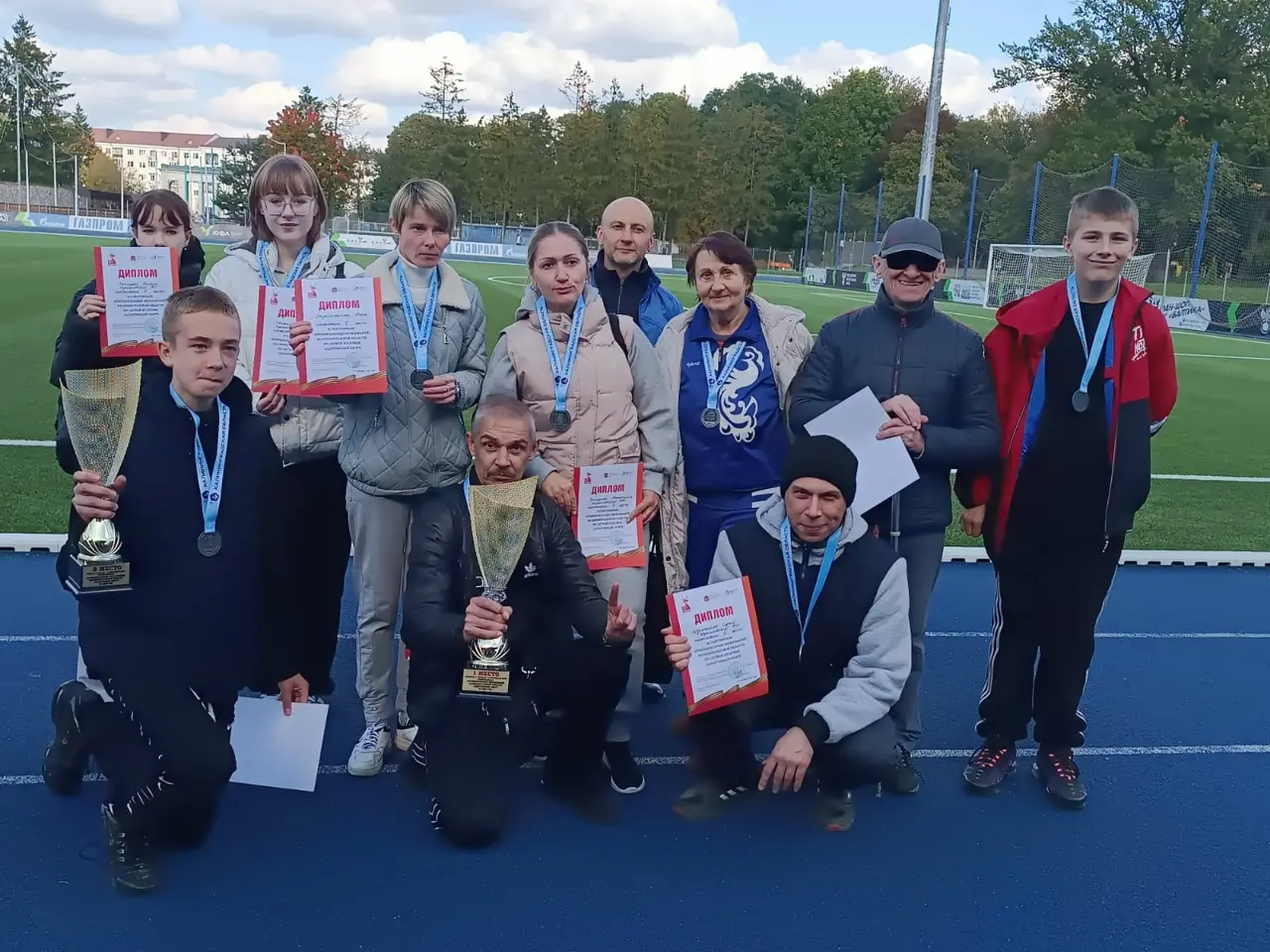 Команда Черняховска с кубками, медалями и дипломами на спортивной площадке